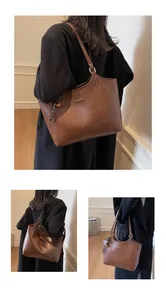 Detail of brown faux leather tote bag with vintage oil wax texture and golden bell charm
