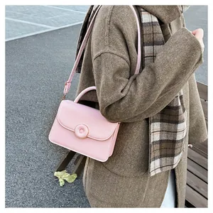 Detail of pink faux leather handbag with circular clasp in an autumn outdoor scene