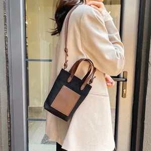 Minimalist black canvas tote with brown leather straps shown on a model in chic attire