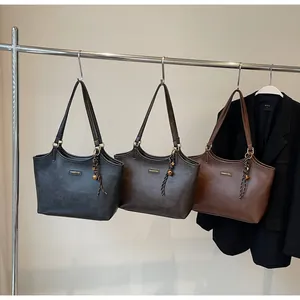 Three large tote bags in black, dark brown, and caramel colors on a metal hanger