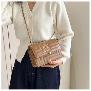 Close-up of brown quilted bag showing chevron texture, gold logo, and tassel detail