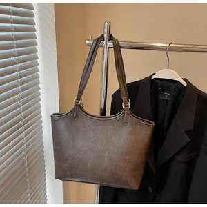 Detail of deep brown tote bag featuring vintage leather texture and gold hardware rings