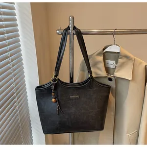 Close-up of matte black leather tote bag with fashion tag and bell charm detail