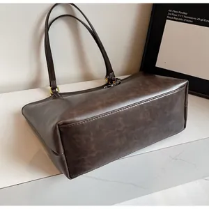 Detail shot of vintage dark brown tote bag showing leather texture and gold hardware