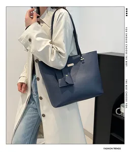 Detail of navy blue leather tote bag with gold metal plate and mini hanging pouch
