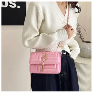 Pink quilted leather crossbody bag with tassel and gold chain strap shown on model