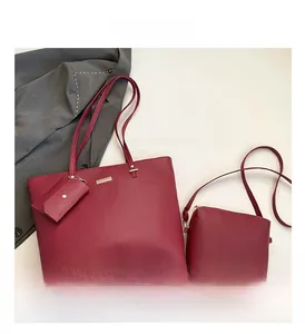 Macro detail of wine red tote bag set showing pebble leather texture and metallic logo plate
