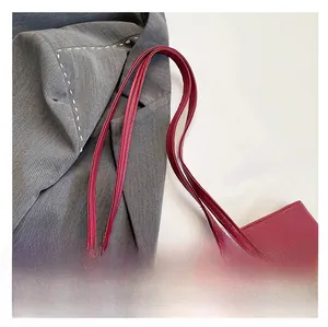 Detail of burgundy textured leather tote bag with comfortable double straps and gold studs