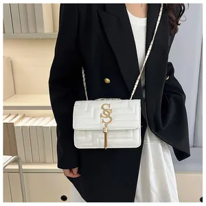 Detail of white quilted handbag with gold SSS logo and fringe on a chain strap