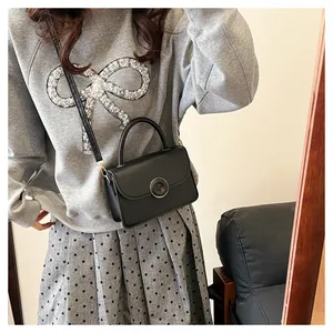 Classic black PU leather handbag detail showing the gold round buckle and top handle