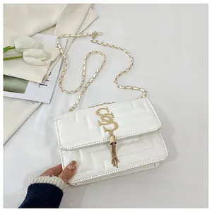 Detail of white quilted crossbody bag with golden tassel buckle and chain strap