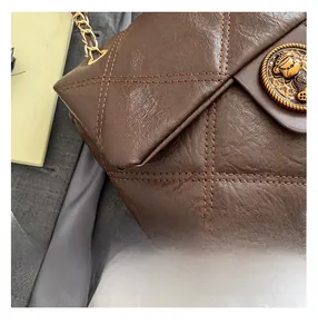 Nahaufnahme der gesteppten braunen Ledertasche mit goldenem Bärenlogo und Kette