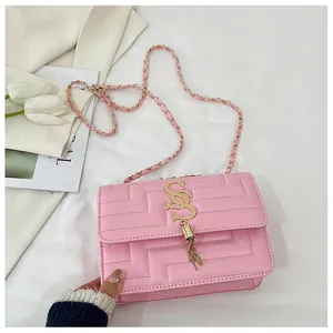 Detail of pink quilted square bag with gold SS logo and elegant metal fringe tassels