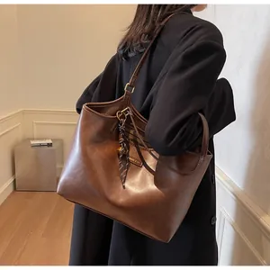 Close-up of brown faux leather tote bag with FASHION & BAG label and shoulder strap