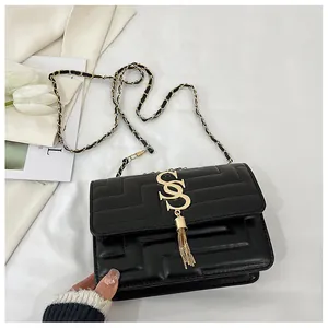 Detail view of black quilted square bag with gold SS logo and elegant chain strap