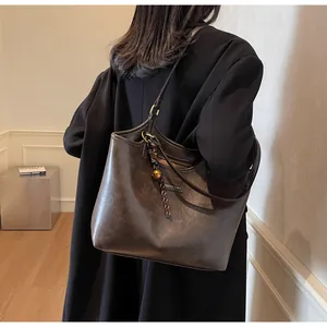 Brown vintage leather tote bag detail with decorative pendant on a model in a studio