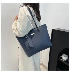 Close-up of navy blue pebbled leather tote bag with gold hardware on a shoulder model