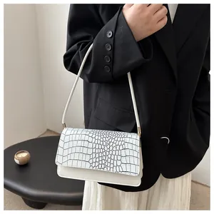 Close-up of elegant white crocodile pattern handbag styled with a black blazer