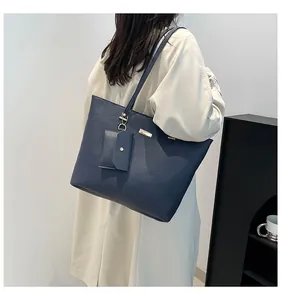 Detail of navy blue tote bag featuring lychee grain leather and golden metal logo tag