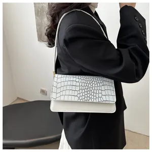 Detail of white crocodile pattern shoulder bag featuring elegant gold hardware on the strap
