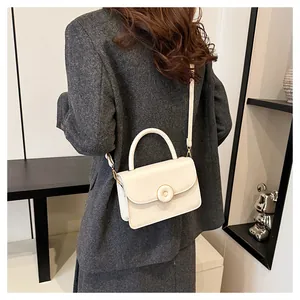 Detail of minimalist cream leather crossbody bag featuring gold ring buckle and sleek handle
