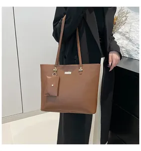 Detail of brown tote bag with leather texture, metal hardware and mini coin purse charm
