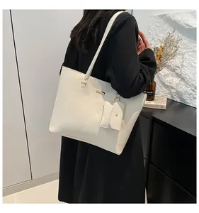 Detail of cream white tote bag set with textured leather and hanging small square pouch