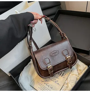 Detail of vintage brown saddle bag featuring FASHION embossing and metallic buckles