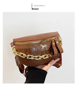 Detail van borsttas met krokodillenpatroon, goudkleurig logo en jacquard riem