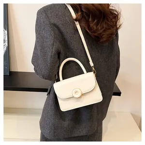 Detailed view of the cream white structured handbag with golden circular buckle and strap