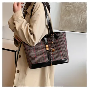 Detail of wool blend plaid tote bag with black leather trim and gold metal pendant
