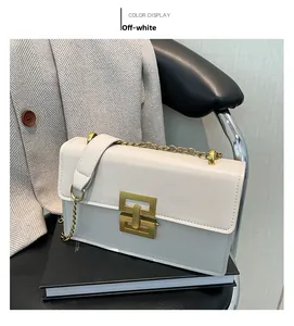 Detail der cremeweißen Umhängetasche mit goldener Hardware und Kette auf Büchern