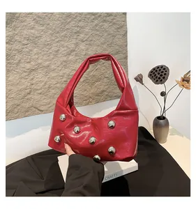 Detail of red crescent hobo bag with silver ball rivets and glossy oil wax leather finish