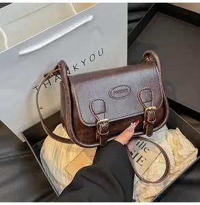 Detail of dark brown vintage PU saddle bag with gold buckles and fashion logo