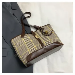 Close-up of vintage yellow plaid tote bag with brown leather trim and golden clasp