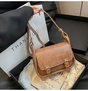Detail of vintage brown PU leather saddle bag with decorative buckles and fashion patch