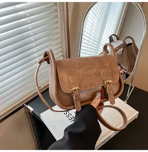Macro detail of brown PU leather saddle bag with double buckle straps and fashion logo