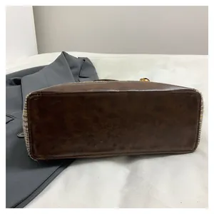 Detail view of the brown leather base and vintage plaid fabric of the tote bag