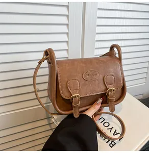 Close-up of vintage brown PU leather saddle bag with fashion engraving and metal buckles