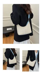 Détail du sac hobo en paille tressée avec bordure en cuir bleu ciel et boucles dorées