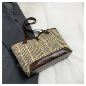 Top view of large plaid tote bag in beige and yellow with leather handles and a grey blazer