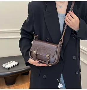 Detail of vintage dark brown PU leather crossbody bag with double buckle flap design