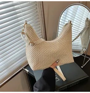 Détail du sac à bandoulière tressé crème avec lanières en cuir blanc et zips dorés