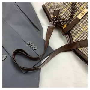 Detail of tweed tote bag featuring houndstooth pattern and golden buckle closure