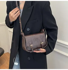 Detailed side view of a vintage dark brown PU leather saddle bag with buckle straps