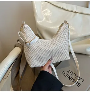 Détail du sac lune tressé crème avec bandoulière en cuir et finitions dorées pâles