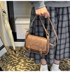 Brown vintage PU leather saddle bag with double buckle straps and metal fashion label