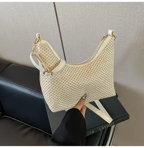 Gros plan du sac hobo tressé beige avec bandoulière blanche et détails dorés