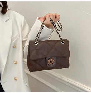 Detail der dunkelbraunen Stepptasche mit Metallkette und Bären-Drehverschluss