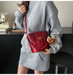 Détail du sac seau rouge matelassé avec fermoir doré et breloque peluche sur modèle